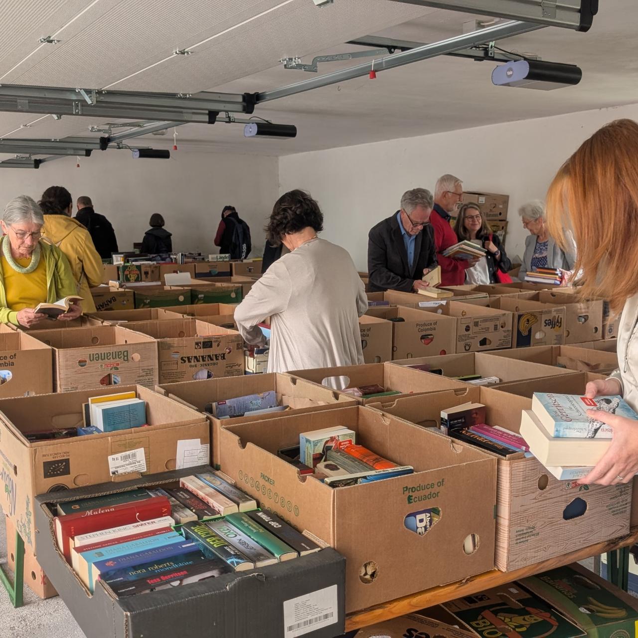 Menschen stöbern in Bücherkisten